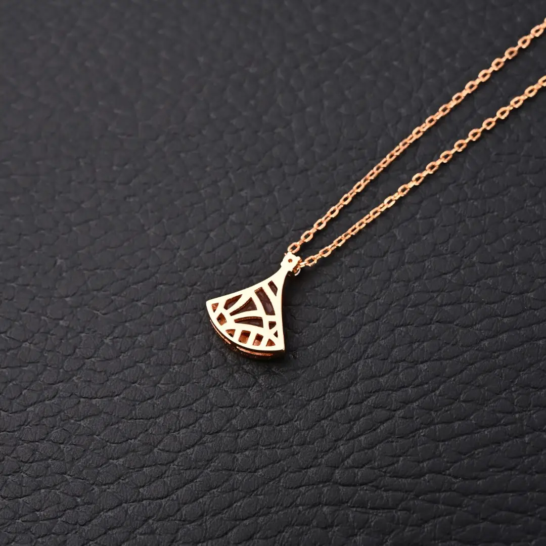 BVLGARI Diva fan-shaped necklace featuring red agate and white mother of pearl, set on a delicate chain against a textured black background.