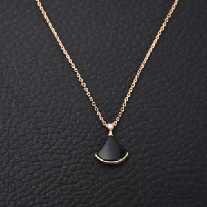 Unknown brand gold necklace with black fan-shaped pendant and small clear gemstone detail on chain