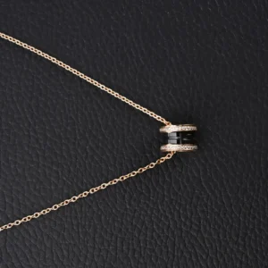 Bvlgari B.Zero1 necklace black ceramic ring rose gold chain with diamond accents on black leather background