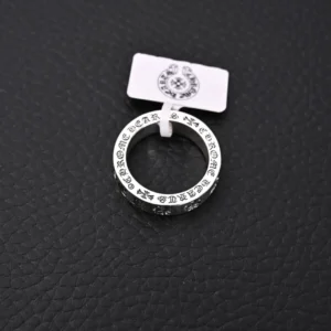 Chrome Hearts CH Forever Sanskrit Cross Ring displayed on a textured black surface, featuring intricate engravings and a tag indicating its brand.