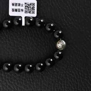 Chrome Hearts Silver Bead Obsidian Bracelet featuring glossy black obsidian beads and a silver logo bead, set against a textured black background.