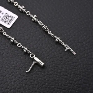 Chrome Hearts CH cross pendant necklace featuring intricate silver design and hallmark details, displayed against a textured black background.