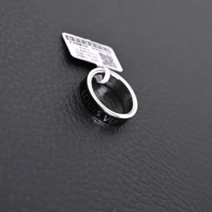 Louis Vuitton LV X Nigo co-branded enamel ring displayed on a textured surface, featuring engraved branding and a product tag.