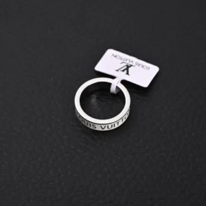Louis Vuitton LV X Nigo co-branded enamel ring displayed on a textured black surface, featuring the brand name inscribed around the band.