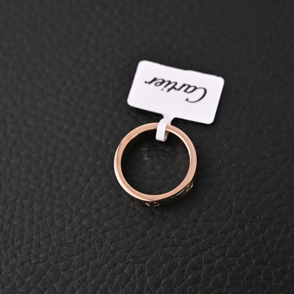 Cartier ring rose gold smooth metal circle band accessory with brand tag on black textured surface