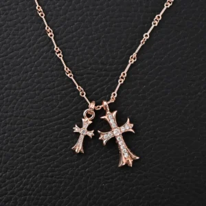Chrome Hearts double cross pendant necklace featuring two intricately designed cross charms, one larger and embellished with rhinestones, on a delicate chain, set against a textured black background.