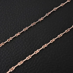 Chrome Hearts double cross pendant necklace featuring a delicate rose gold chain design on a textured black background.