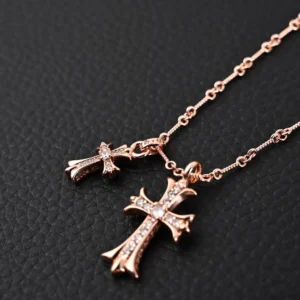 Chrome Hearts double cross pendant necklace featuring two intricately designed cross pendants in rose gold with sparkling details, displayed on a textured black background.