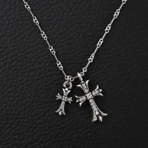 Chrome Hearts Double Cross Pendant Necklace featuring two cross charms, one large and one small, adorned with rhinestones, displayed on a textured black background.