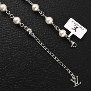 Louis Vuitton LV Pearls DA necklace featuring white pearl beads, Damier engraved metal accents, and a silver chain with a logo pendant, set against a textured black background.