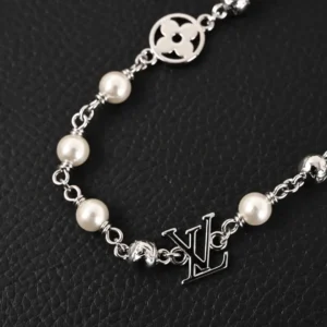 Louis Vuitton LV Pearls DA necklace featuring Damier engraved metal beads and white pearls, showcasing the iconic LV logo and classic design on a textured black background.