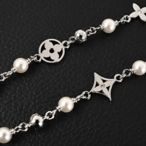 Louis Vuitton LV Pearls DA necklace featuring Damier engraved metal beads and white pearls, showcasing luxury jewelry design on a textured black background.