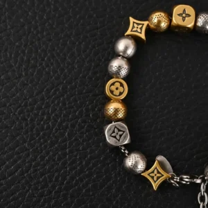 Antique gold and silver bead bracelet featuring Louis Vuitton motifs, displayed against a textured black background, representing the Louis Vuitton LV Damier Party design.