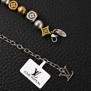 Louis Vuitton antique gold bead bracelet with signature logo tag on a textured black background, showcasing luxury design and craftsmanship.