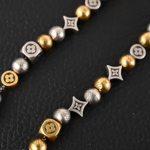 Louis Vuitton LV DamierPar necklace featuring antique gold and silver beads, intricate logo designs, and a luxurious aesthetic on a dark background.