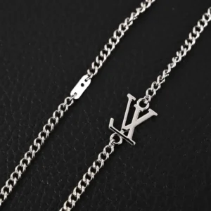 Louis Vuitton Damier Rings necklace featuring lustrous brass, engraved LV logo, and adjustable chain on black background.