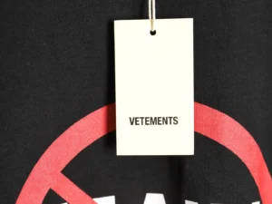 Vetements logo tag on black T-shirt with red circle design, emphasizing designer branding and unisex style.