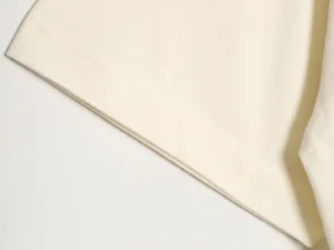 Close-up of RHUDE 25ss retro logo print T-shirt sleeve detail, showcasing fabric texture and stitching.