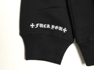 No brand visible black sweatshirt sleeve with white Gothic-style embroidered text and cross symbols