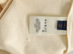 Label on a Louis Vuitton hoodie showcasing fabric care instructions and size information, emphasizing quality and authenticity.