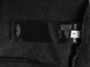 Balenciaga hoodie size label showing "L" on a black fabric background, emphasizing luxury replica fashion details.