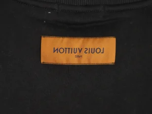 Louis Vuitton label on a black hoodie, showcasing brand authenticity and premium quality.