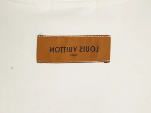 Louis Vuitton clothing label brown fabric tag with black logo text on white textile background