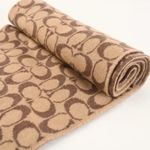 Coach Disney Double-Sided Logo Wool Scarf featuring a repeating logo pattern in brown and beige, showcasing its luxurious wool and cashmere blend, ideal for warmth and comfort.
