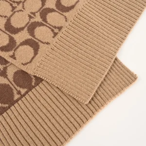 Coach Disney Double-Sided Logo Wool Scarf featuring a luxurious wool and cashmere blend, showcasing a classic logo pattern in beige and brown tones, with ribbed edges for added texture.