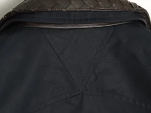 The image shows a close-up view of a fabric item with a black base and brown leather woven detail along the top edge, but it doesn't provide enough information about brand, product type, model, or specifications for SEO-optimized alt text according to your rules. Please provide an image with clear product details visible.