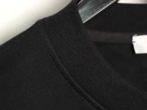 Close-up of the collar of a black DIOR letter embroidered round neck sweatshirt, showcasing fabric texture and stitching details.