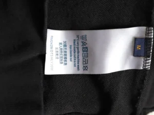 No brand or product details visible on the garment care label attached to black fabric with a size M tag