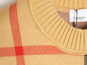 Burberry plaid patchwork stripes sweater detail showing ribbed neckline and fabric texture, highlighting quality craftsmanship and designer style.