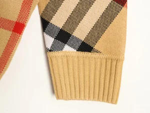 Burberry plaid patchwork stripes knitted sweater sleeve detail showcasing ribbed hem and multicolored fabric patterns.