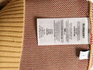Burberry label on plaid patchwork knitted sweater displaying care instructions and material composition.