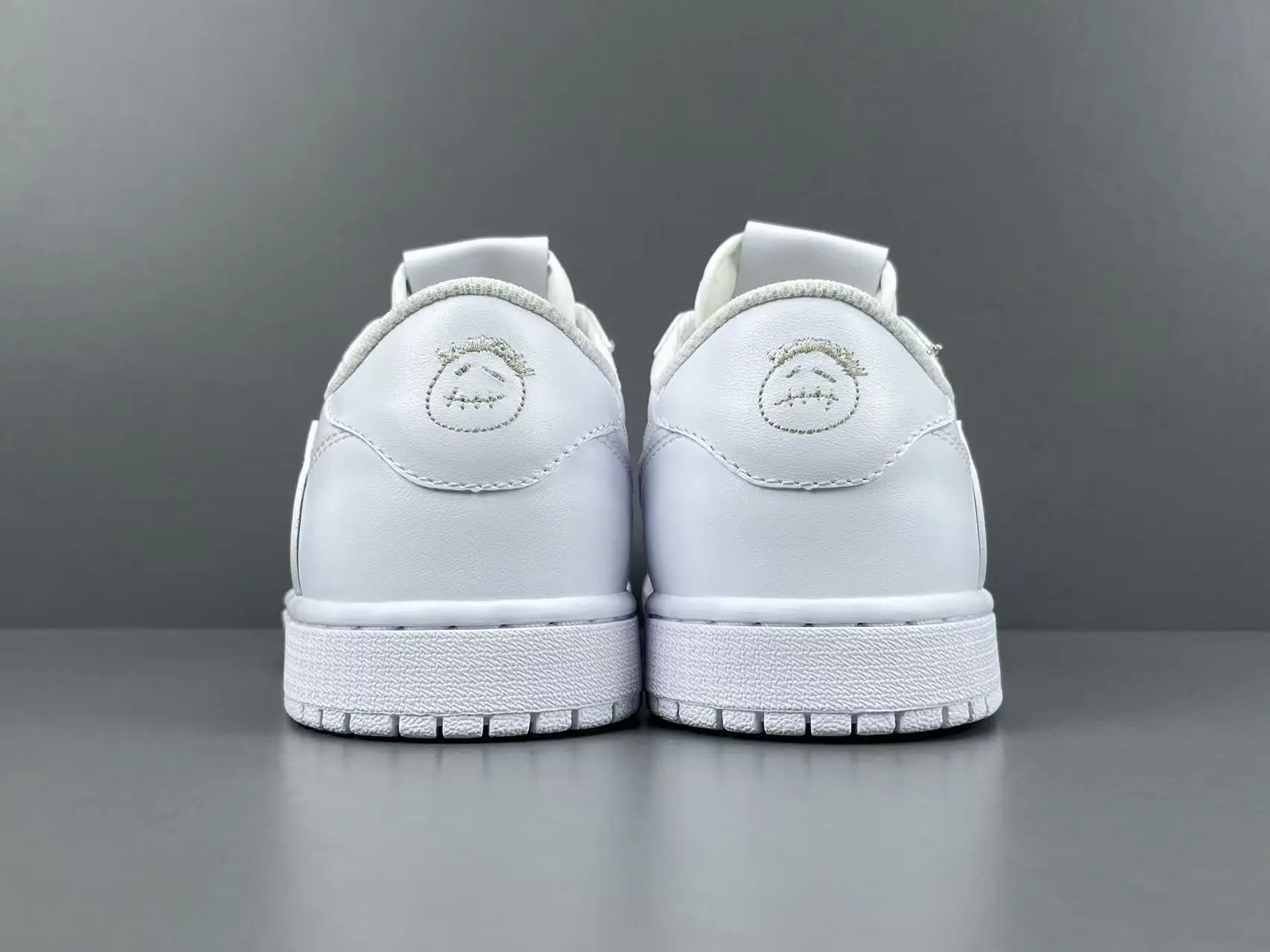 Nike Air Jordan 1 Low OG white colorway leather sneakers with embroidered smiley face logo on heel