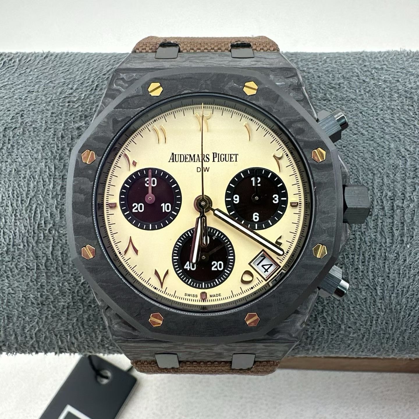 Audemars Piguet Royal Oak 26240CE, 41mm forged carbon fiber case, iconic octagonal bezel with gold hex screws. Retro cream colored dial, Arabic art hour markers, three eye timing dial, 3 o'clock date window. Equipped with the Cal.4401 automatic winding flyback timing movement, 40 gems, 70 hours of power reserve, and support for flyback timing function. The forged carbon material is lightweight and impact resistant, paired with a canvas strap, balancing a sporty and rugged temperament with a retro aesthetic. The scarce carbon shell version.