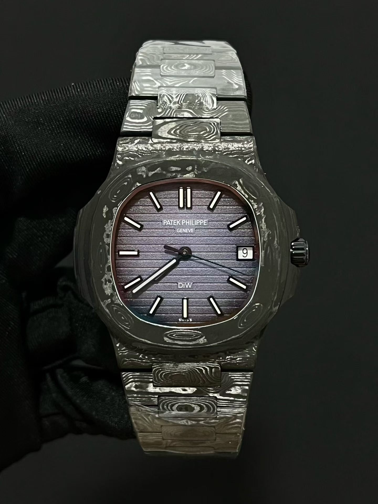 Patek Philippe
Nautilus 5711 DiW | Aesthetics of Carbon Fiber Modification
As a well-known watch modification factory in the industry, DiW has given the Patek Philippe Nautilus 5711 a completely different trendy style, bringing the charm of composite materials to the extreme and gaining a large number of watch players' pursuit.
This modified 5711 opens a new chapter in composite materials for wristwatches, blending the lightweight texture of carbon fiber with the warm and smooth touch of ceramics, enhancing its aesthetic recognition.
The case is made of high-end carbon fiber and embellished with stainless steel components. The overall black tone is interwoven with irregular textures of carbon fiber, making it visually recognizable. The dial retains classic hour markers and hands, and the luxurious and elegant original factory heritage is still preserved.
The bottom cover is made of stainless steel substrate, treated with black coating, and the overall color tone is highly uniform.
The watch strap is a major highlight of the entire watch, with a combination of carbon fiber and stainless steel. The carbon fiber texture layer flows like smoke and clouds, creating a strong atmosphere for hands-on play.
The core uses Patek Philippe's original integrated 324 movement, with unchanged performance foundation. After the complete reconstruction of DiW, the overall style of the watch is avant-garde, bold, cool and personalized, which is very suitable for young collectors who pursue unique trendy styles.
​