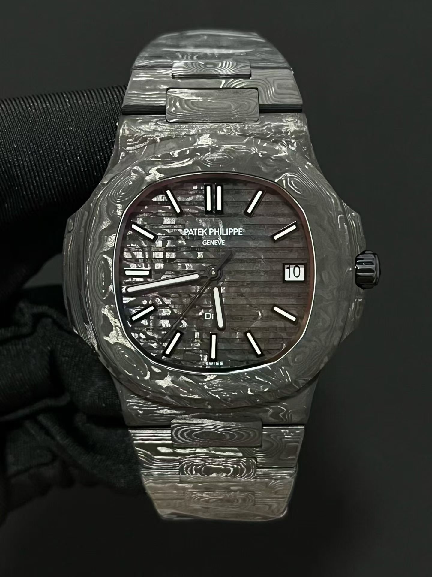 Patek Philippe
Nautilus 5711 DiW | Aesthetics of Carbon Fiber Modification
As a well-known watch modification factory in the industry, DiW has given the Patek Philippe Nautilus 5711 a completely different trendy style, bringing the charm of composite materials to the extreme and gaining a large number of watch players' pursuit.
This modified 5711 opens a new chapter in composite materials for wristwatches, blending the lightweight texture of carbon fiber with the warm and smooth touch of ceramics, enhancing its aesthetic recognition.
The case is made of high-end carbon fiber and embellished with stainless steel components. The overall black tone is interwoven with irregular textures of carbon fiber, making it visually recognizable. The dial retains classic hour markers and hands, and the luxurious and elegant original factory heritage is still preserved.
The bottom cover is made of stainless steel substrate, treated with black coating, and the overall color tone is highly uniform.
The watch strap is a major highlight of the entire watch, with a combination of carbon fiber and stainless steel. The carbon fiber texture layer flows like smoke and clouds, creating a strong atmosphere for hands-on play.
The core uses Patek Philippe's original integrated 324 movement, with unchanged performance foundation. After the complete reconstruction of DiW, the overall style of the watch is avant-garde, bold, cool and personalized, which is very suitable for young collectors who pursue unique trendy styles.
​
