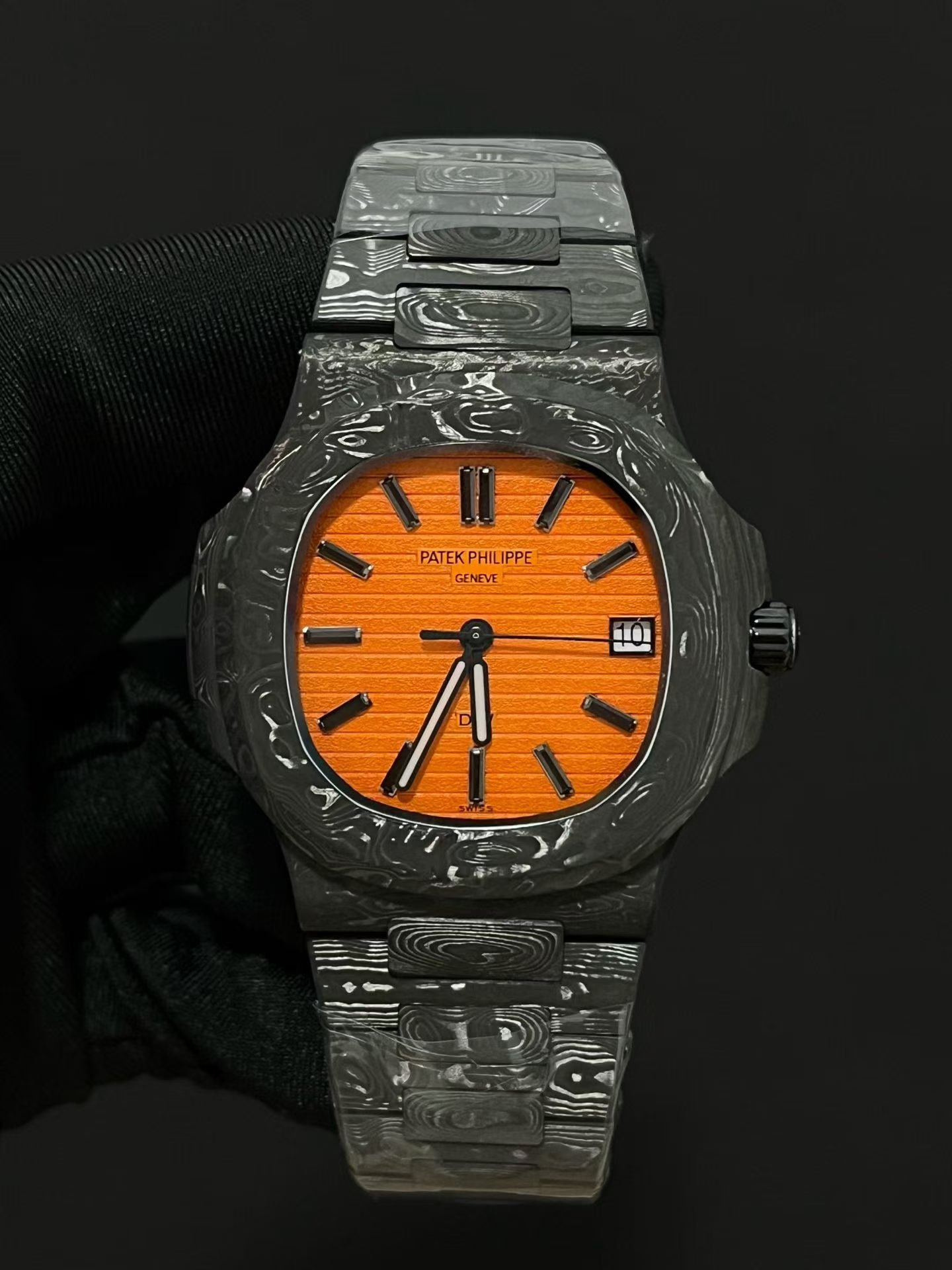 Patek Philippe
Nautilus 5711 DiW | Aesthetics of Carbon Fiber Modification
As a well-known watch modification factory in the industry, DiW has given the Patek Philippe Nautilus 5711 a completely different trendy style, bringing the charm of composite materials to the extreme and gaining a large number of watch players' pursuit.
This modified 5711 opens a new chapter in composite materials for wristwatches, blending the lightweight texture of carbon fiber with the warm and smooth touch of ceramics, enhancing its aesthetic recognition.
The case is made of high-end carbon fiber and embellished with stainless steel components. The overall black tone is interwoven with irregular textures of carbon fiber, making it visually recognizable. The dial retains classic hour markers and hands, and the luxurious and elegant original factory heritage is still preserved.
The bottom cover is made of stainless steel substrate, treated with black coating, and the overall color tone is highly uniform.
The watch strap is a major highlight of the entire watch, with a combination of carbon fiber and stainless steel. The carbon fiber texture layer flows like smoke and clouds, creating a strong atmosphere for hands-on play.
The core uses Patek Philippe's original integrated 324 movement, with unchanged performance foundation. After the complete reconstruction of DiW, the overall style of the watch is avant-garde, bold, cool and personalized, which is very suitable for young collectors who pursue unique trendy styles.
​